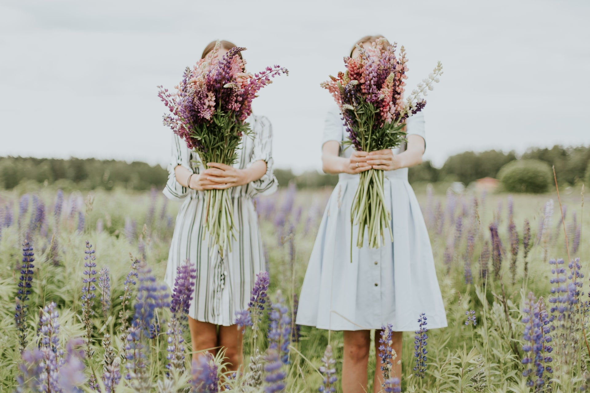 spring photo of two girls holding flower in front of their face