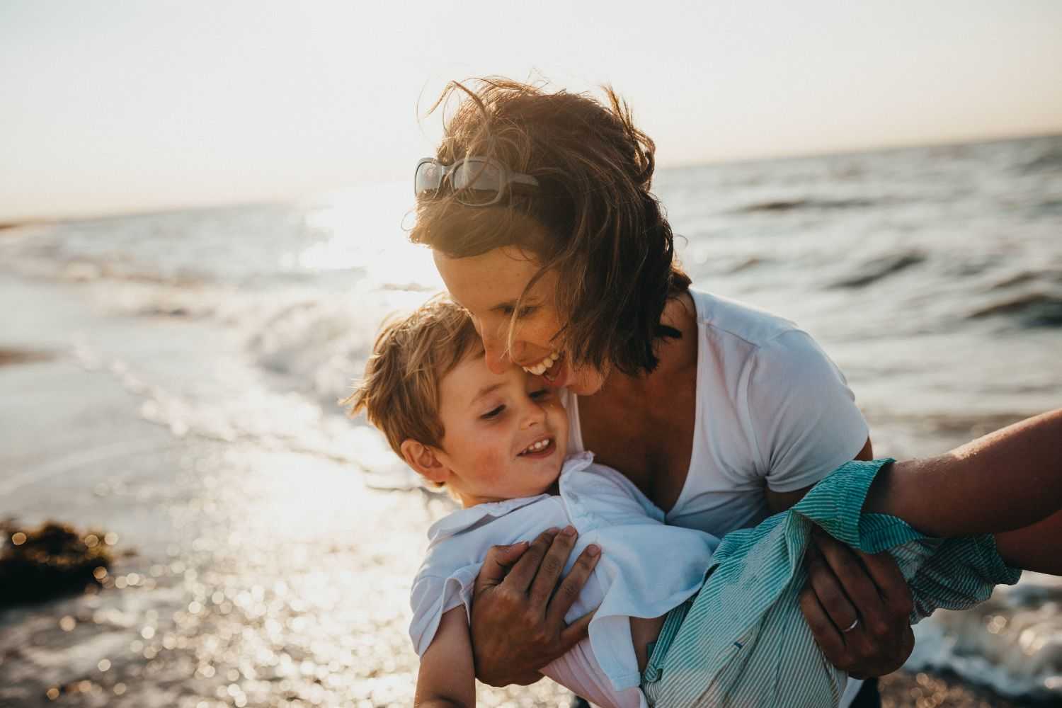 Mom is holding the child by the beach Photo by Xavier Mouton Photographie on unsplash