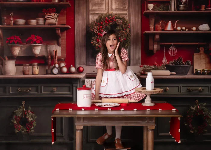 Girl in red dress posing in front of a Christmas Kitchen Photoshoot setup
