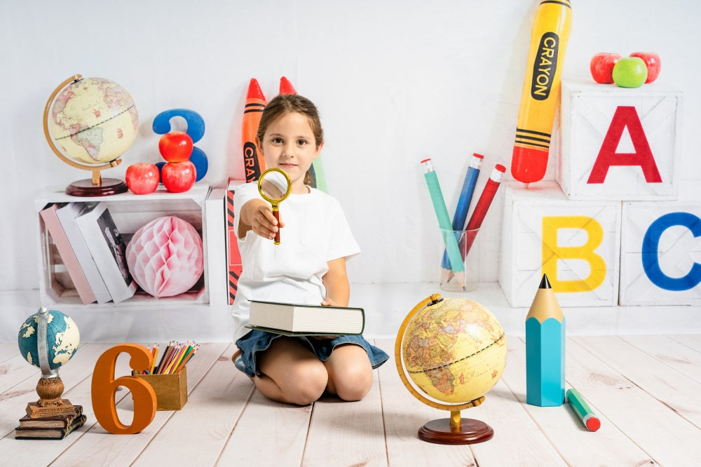 Little girl studying with books and school supplies in a colorful back to school backdrop scene