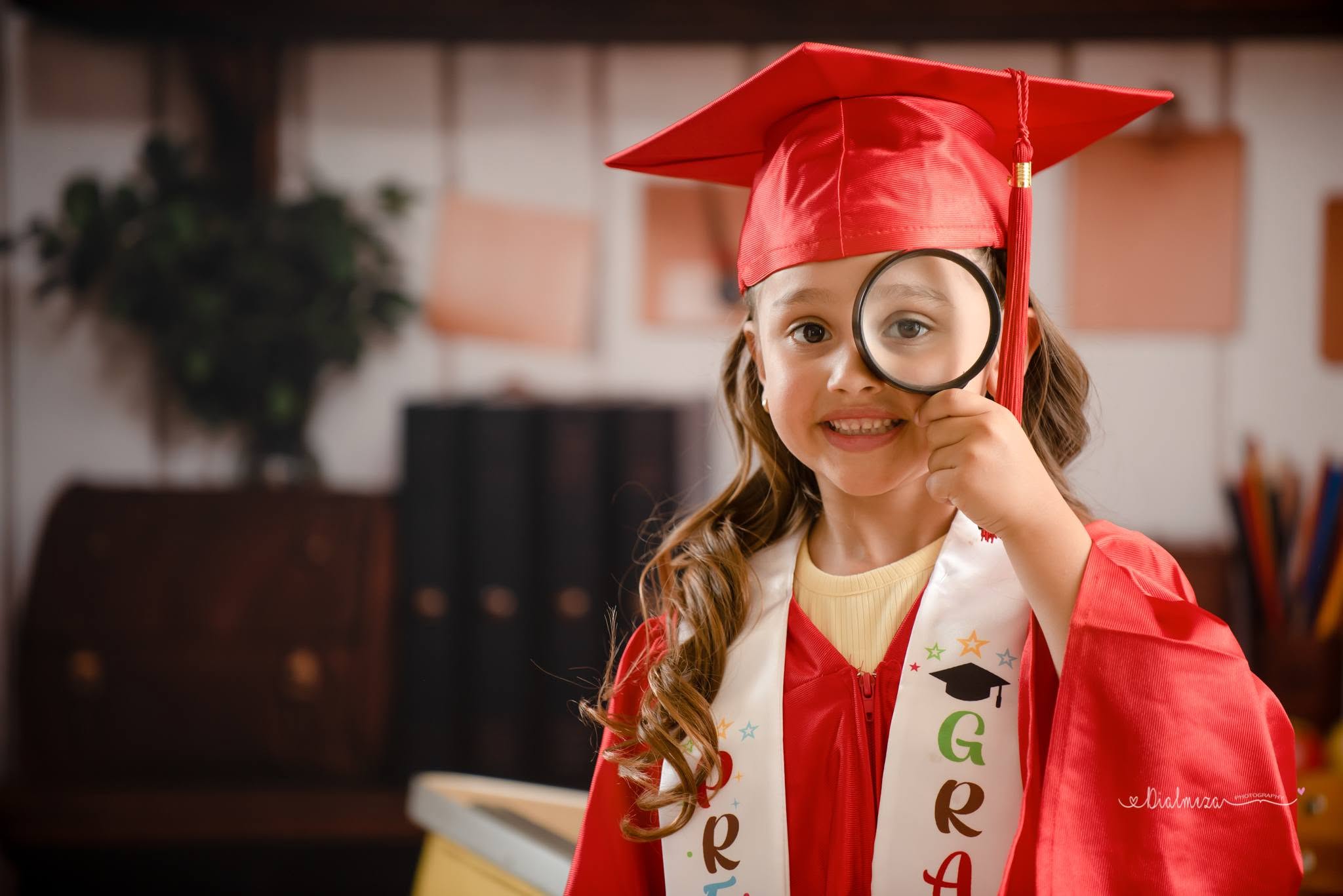 Elementary girl holding a magnifier for her graduation session