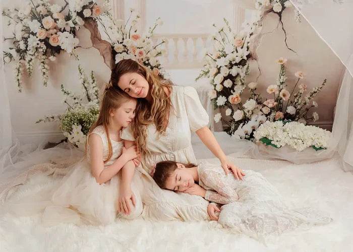 mom and her girls sitting together in a floral themed photo session setup