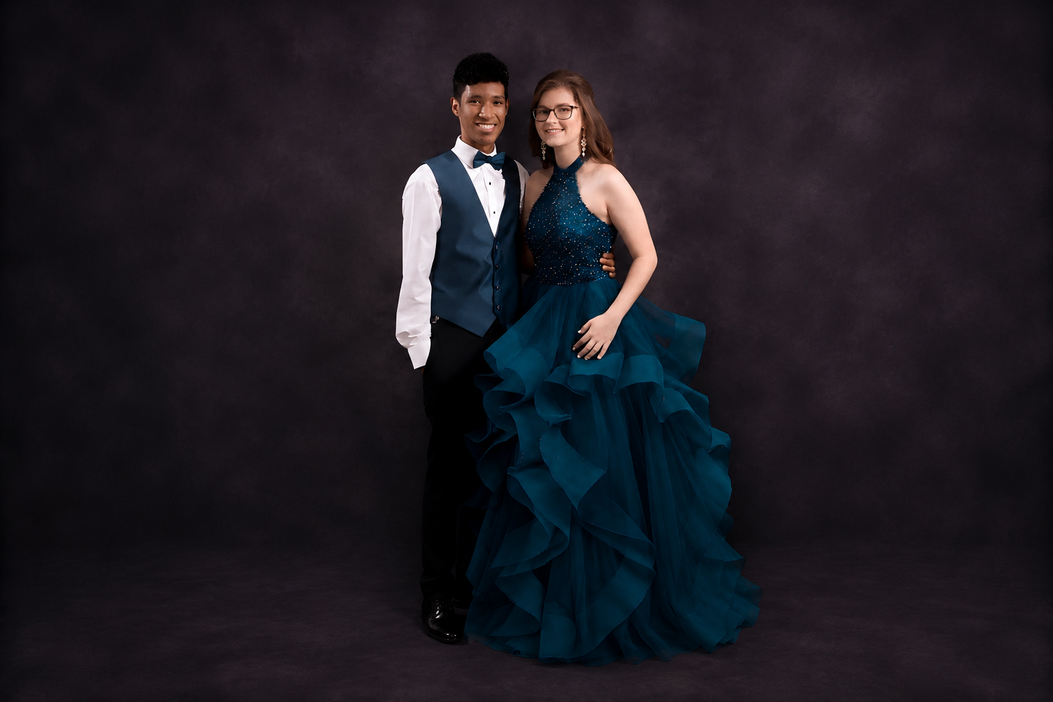 Prom couple in formal teal attire posing for a classic studio portrait.