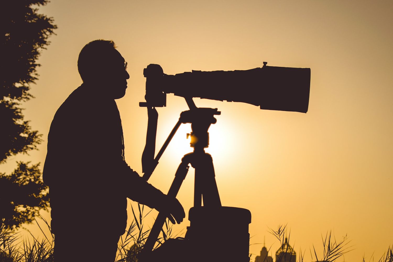 silhouette photo of a photography taking photo with telephoto lens Photo by Jonathan Mabey on Unsplash
