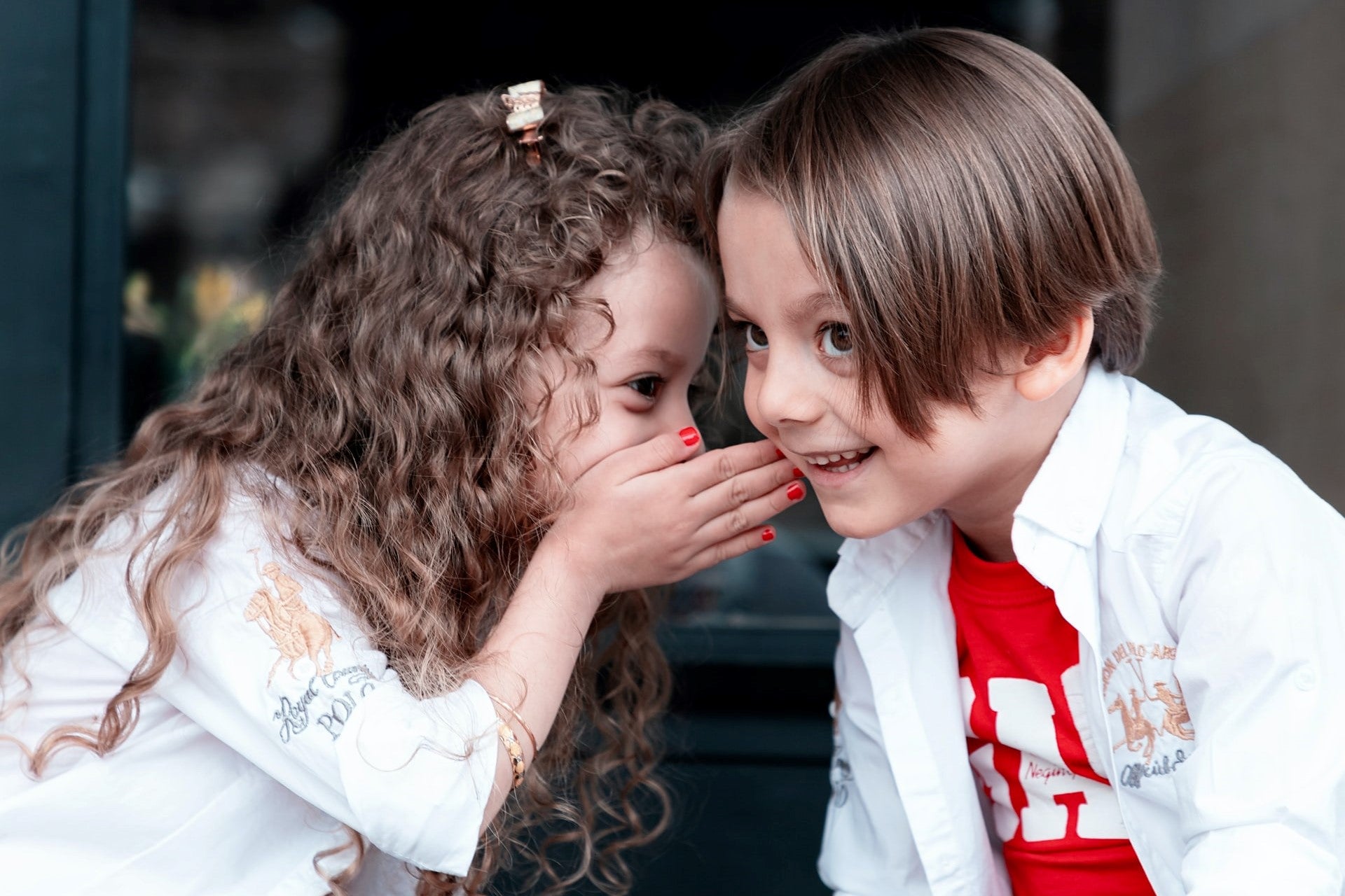 a kids photo of girl whispering with a boy
