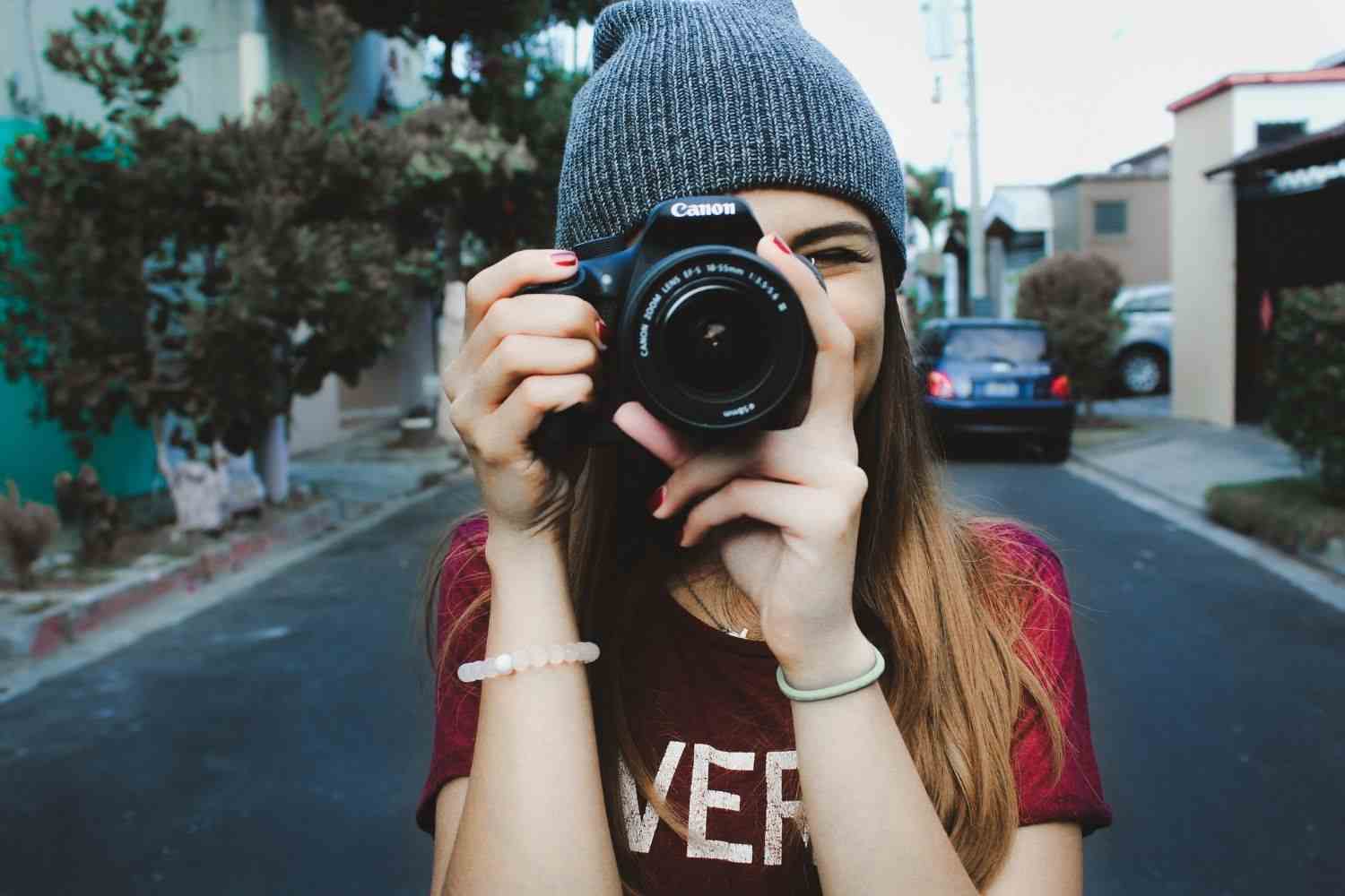 a smiling woman is taking photos with a camera Photo by Max Panam on unsplash
