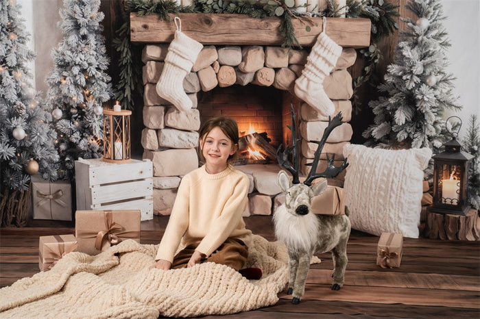 Child sitting in front of a cozy Christmas fireplace photography backdrop
