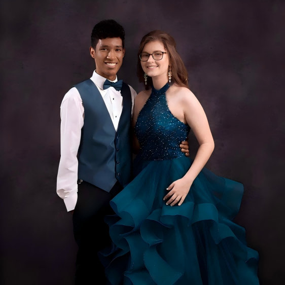 Prom couple in formal teal attire posing for a classic studio portrait.