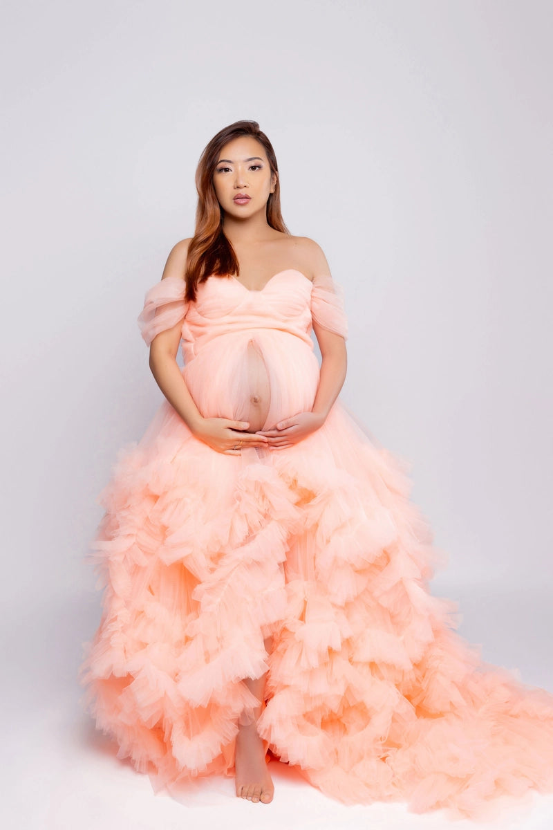 Pregnant woman wearing a pink lace maternity dress for a photo shoot