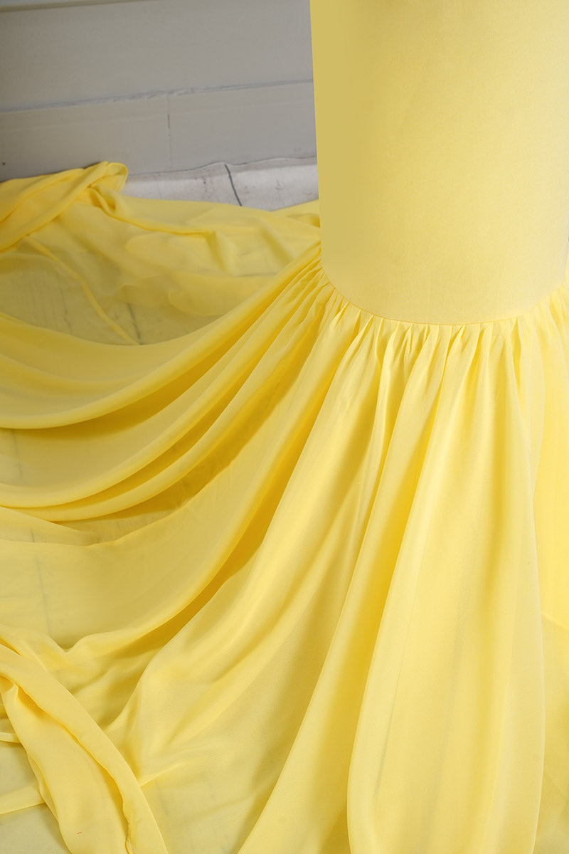 Detail shot of the hemline of a yellow one-shoulder satin maternity gown