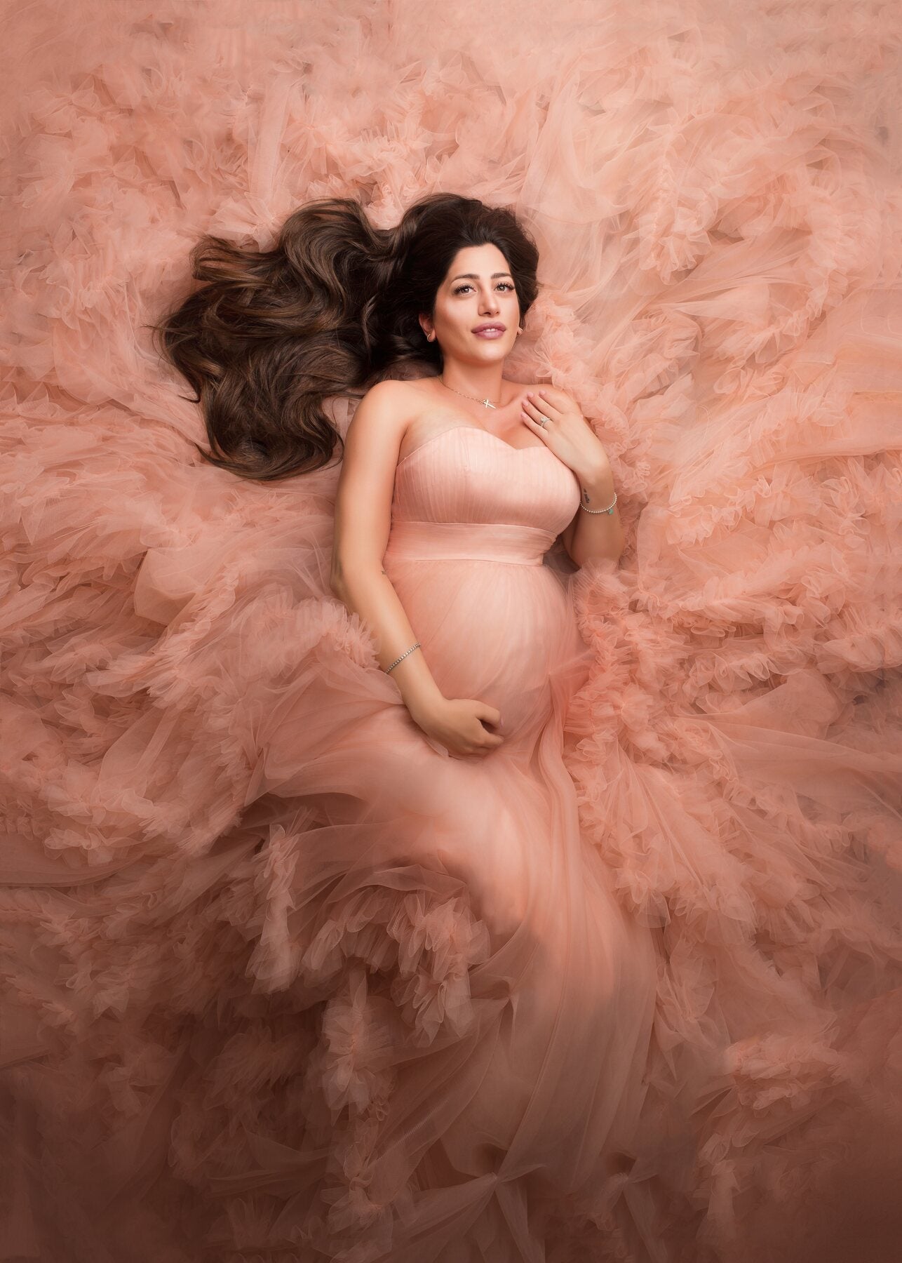 A maternity portrait in a soft floral studio scene